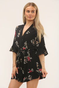 Woman wearing a black floral dress against a white background