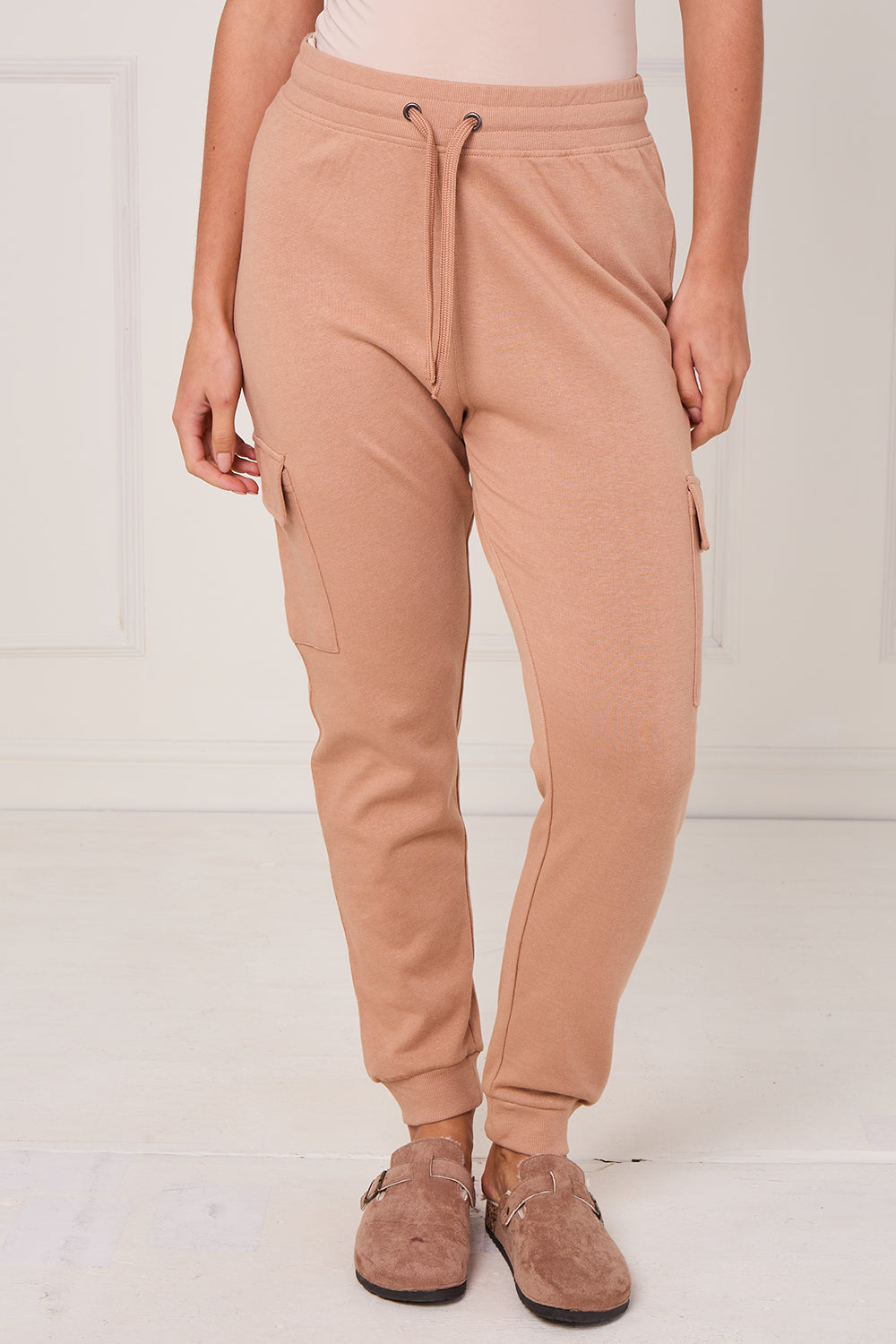 Person wearing tan jogger pants on a white background