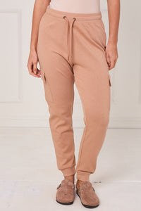 Person wearing tan jogger pants on a white background