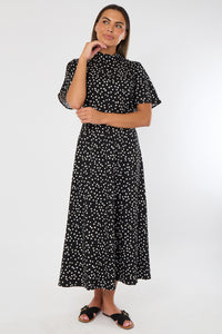 Woman wearing a black dress with white polka dots on a white background