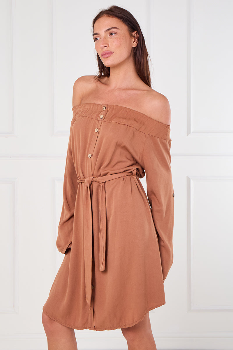 Woman wearing a brown off-shoulder dress against a white background