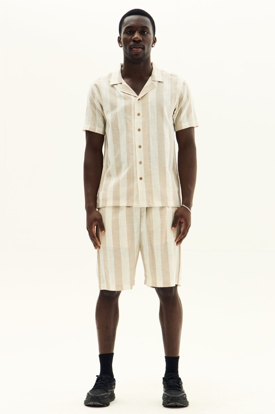 Man wearing a matching beige shirt and shorts set on a white background