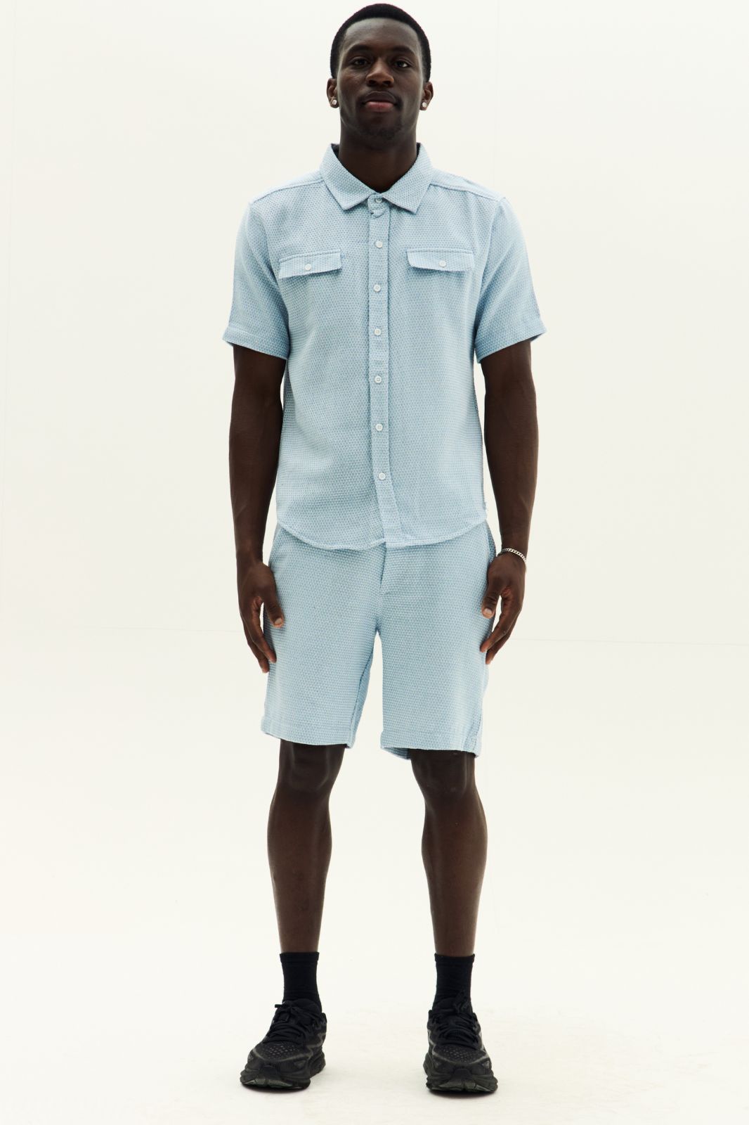 Man wearing a light blue shirt and shorts set on a white background