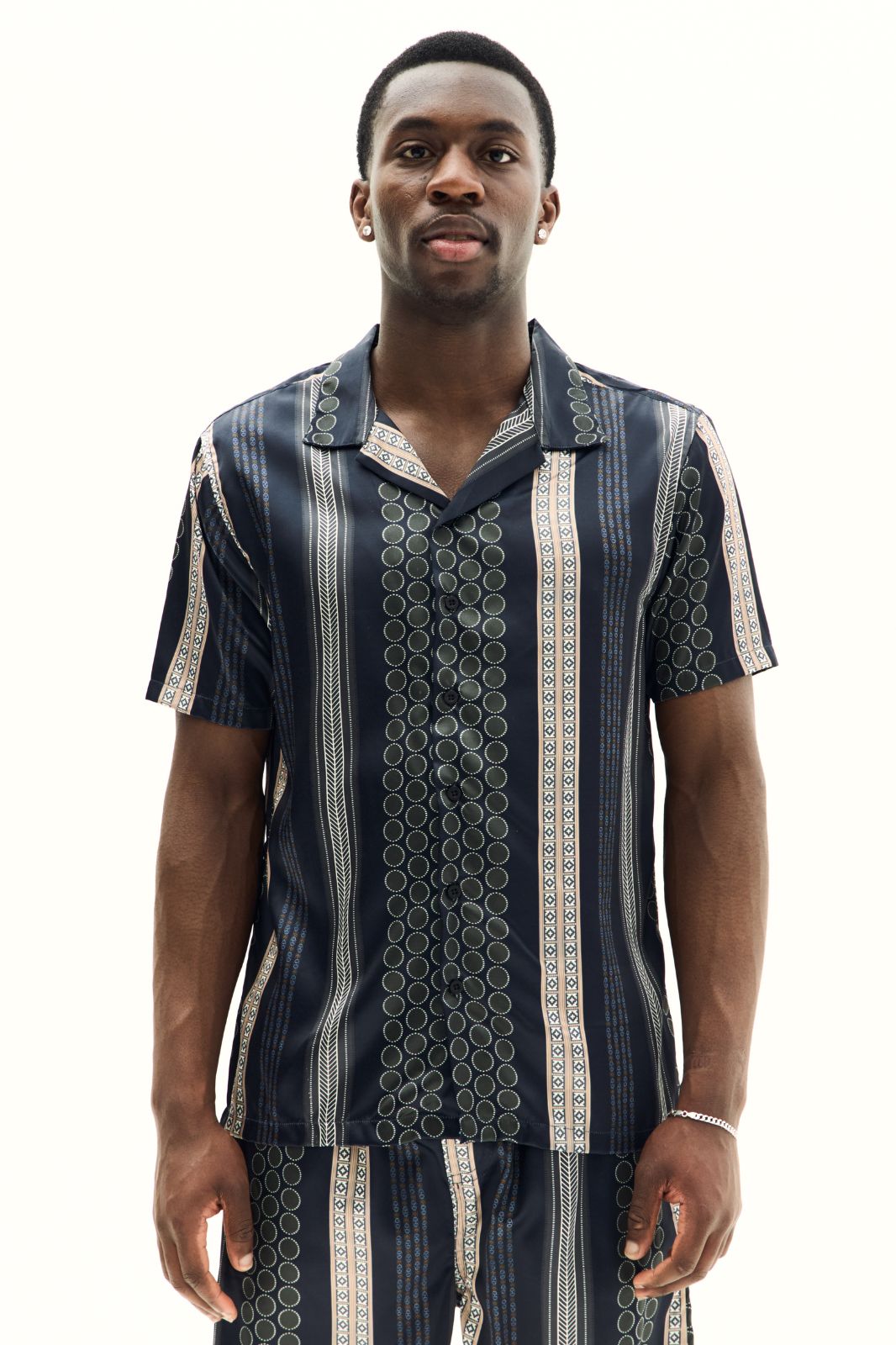 Man wearing a patterned shirt and pants on a white background