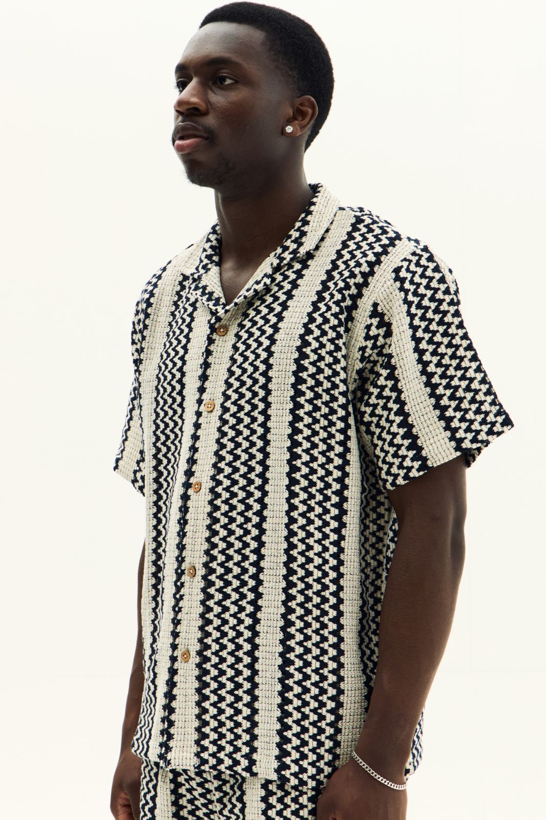 Man wearing a black and white patterned shirt on a white background