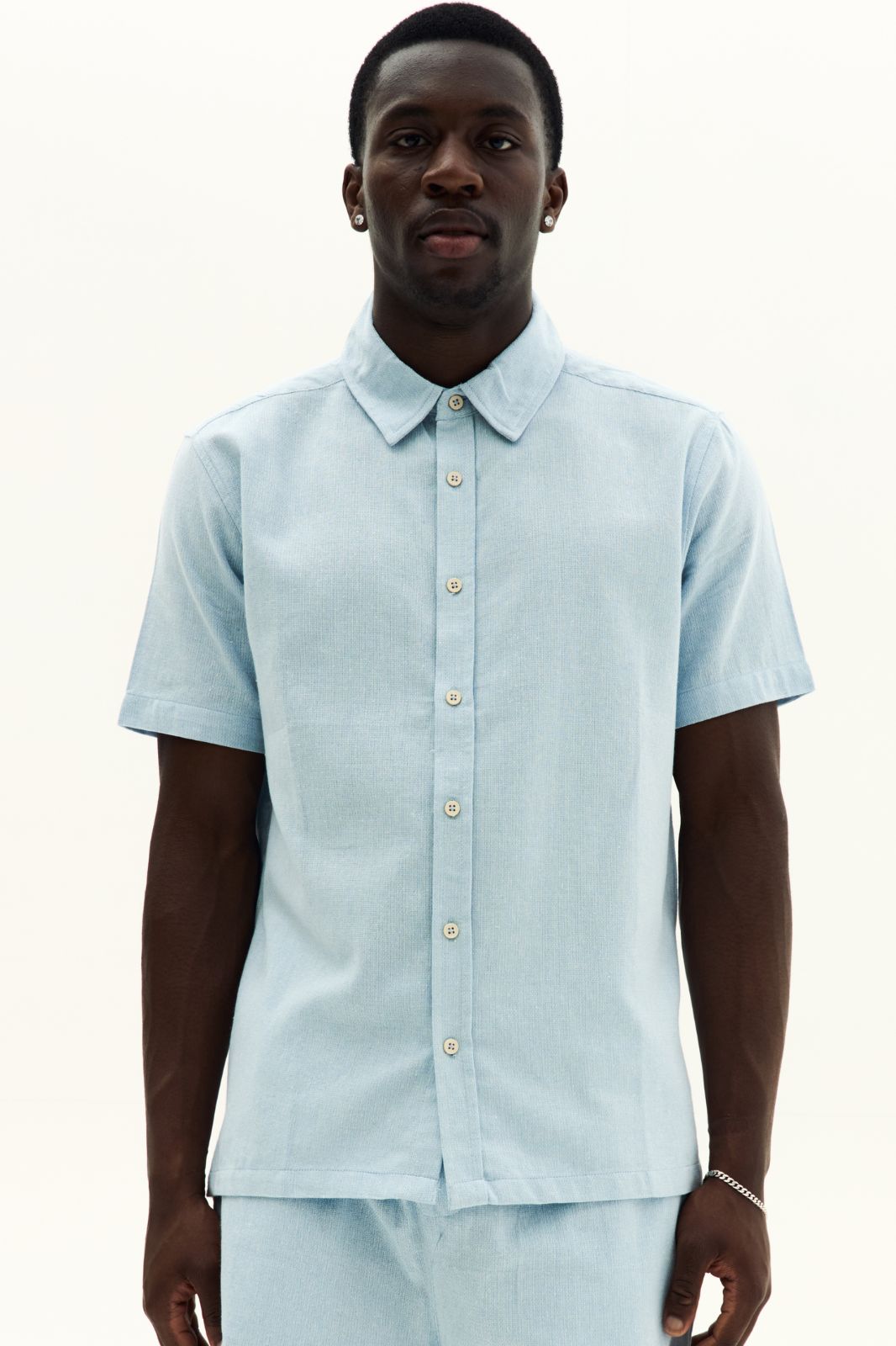 Man wearing a light blue short-sleeve shirt on a white background