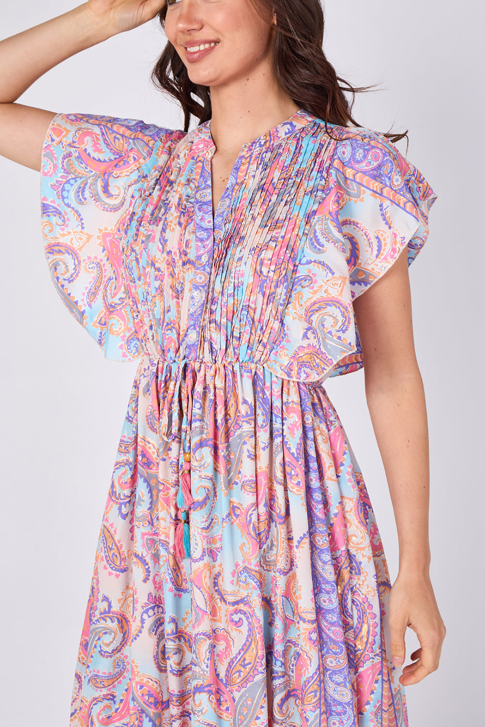 Woman wearing a colorful paisley dress on a white background