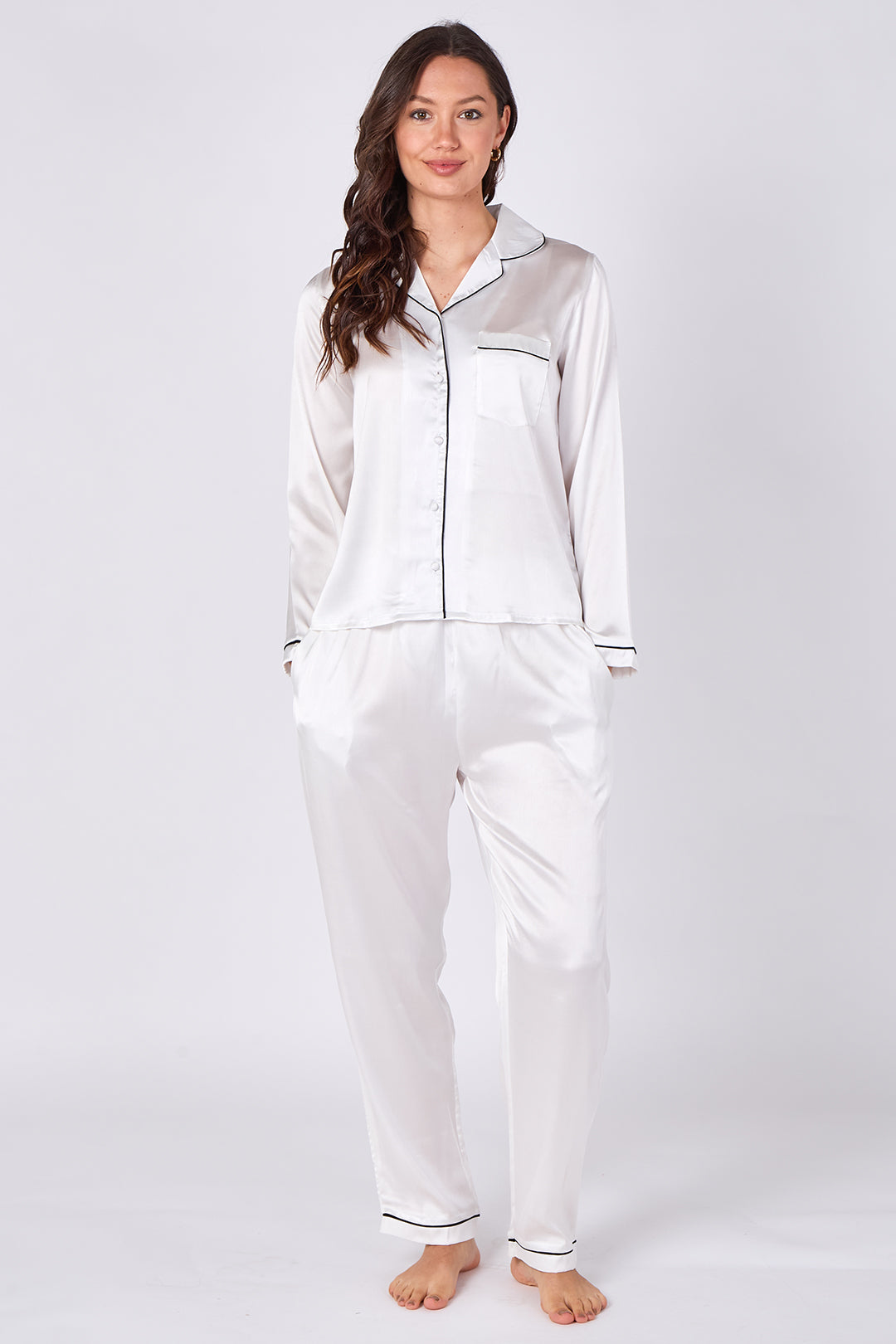 Woman wearing a white satin pajama set on a plain background