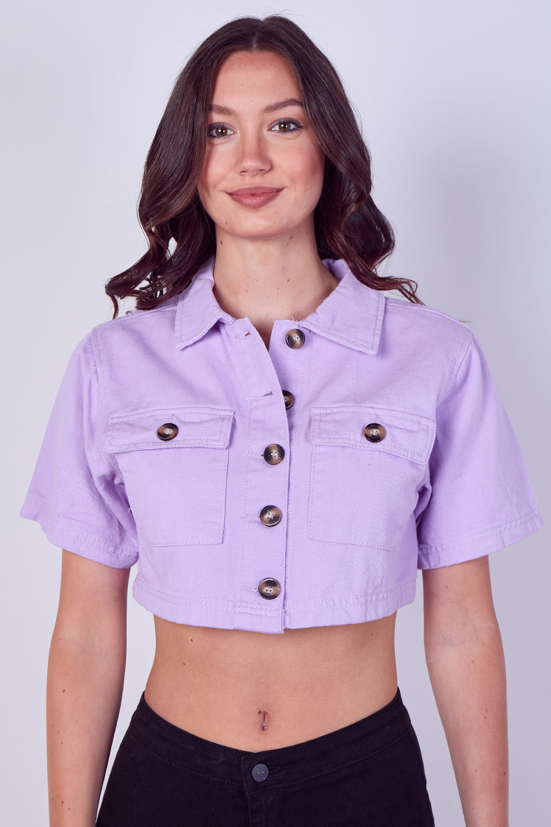 Woman wearing a light purple denim jacket on a plain background