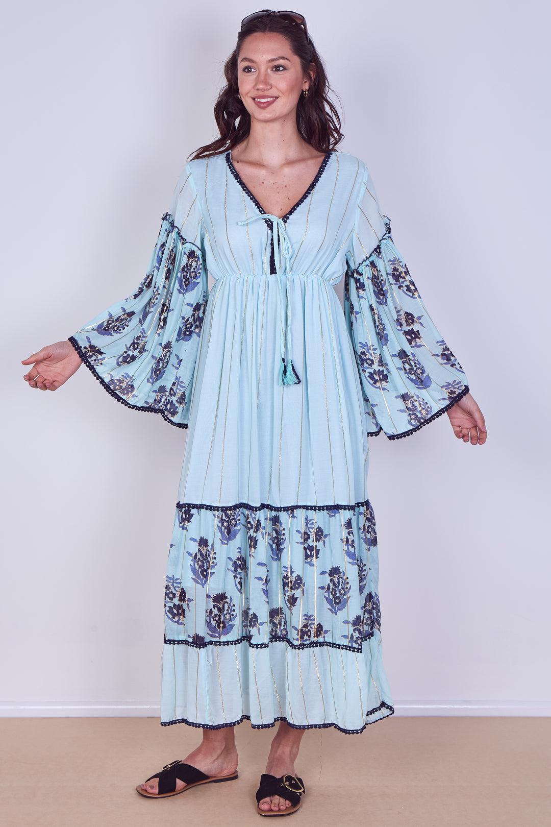 Woman wearing a light blue dress with floral patterns on a white background