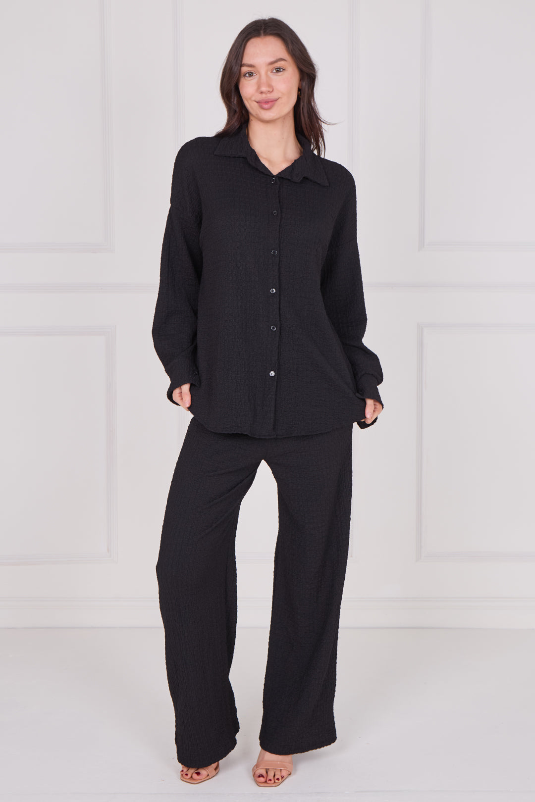 Model wearing a women’s two-piece co-ord set with a long sleeve button-down shirt and matching wide-leg trousers, featuring a relaxed fit and soft textured fabric, styled as an effortless casual outfit.