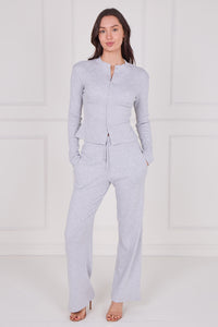 Woman wearing a light gray pajama set against a white background