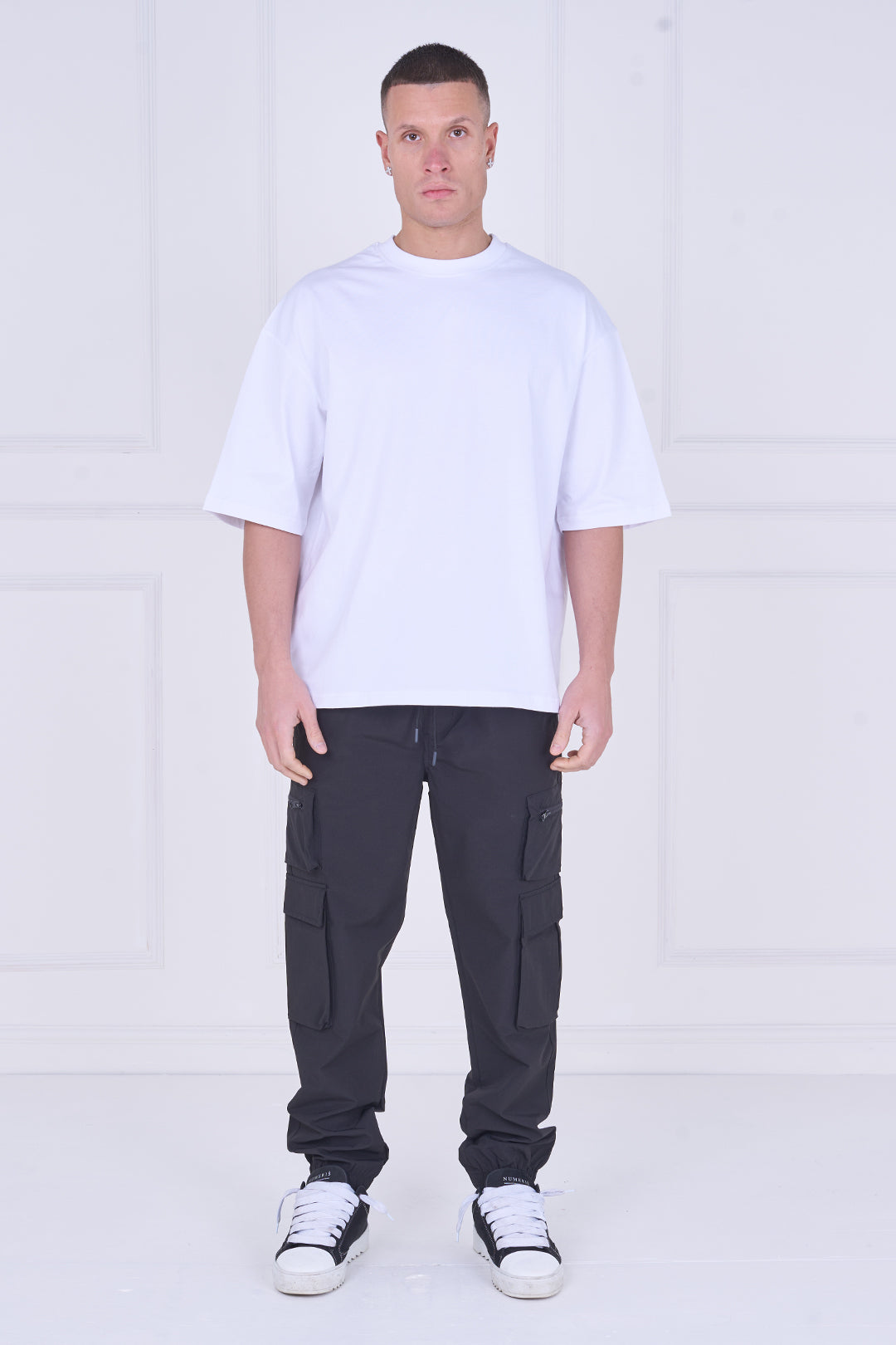 Person wearing a white t-shirt and black pants on a white background