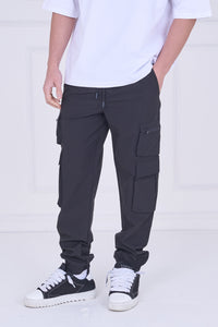 Person wearing black cargo pants and white sneakers on a white background