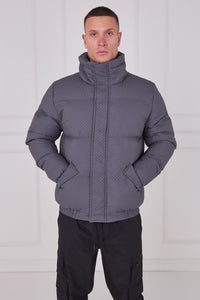 Man wearing a gray quilted jacket against a white background