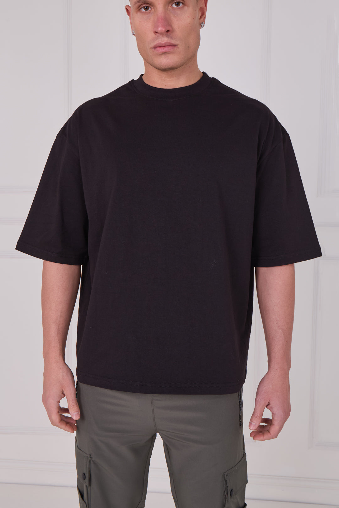 Person wearing a black t-shirt and gray pants against a white background