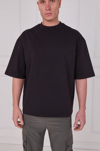 Person wearing a black t-shirt and gray pants against a white background