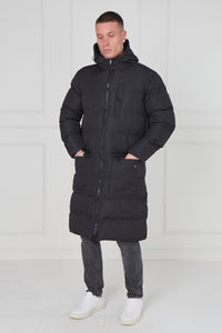 Man wearing a long black puffer coat against a white background