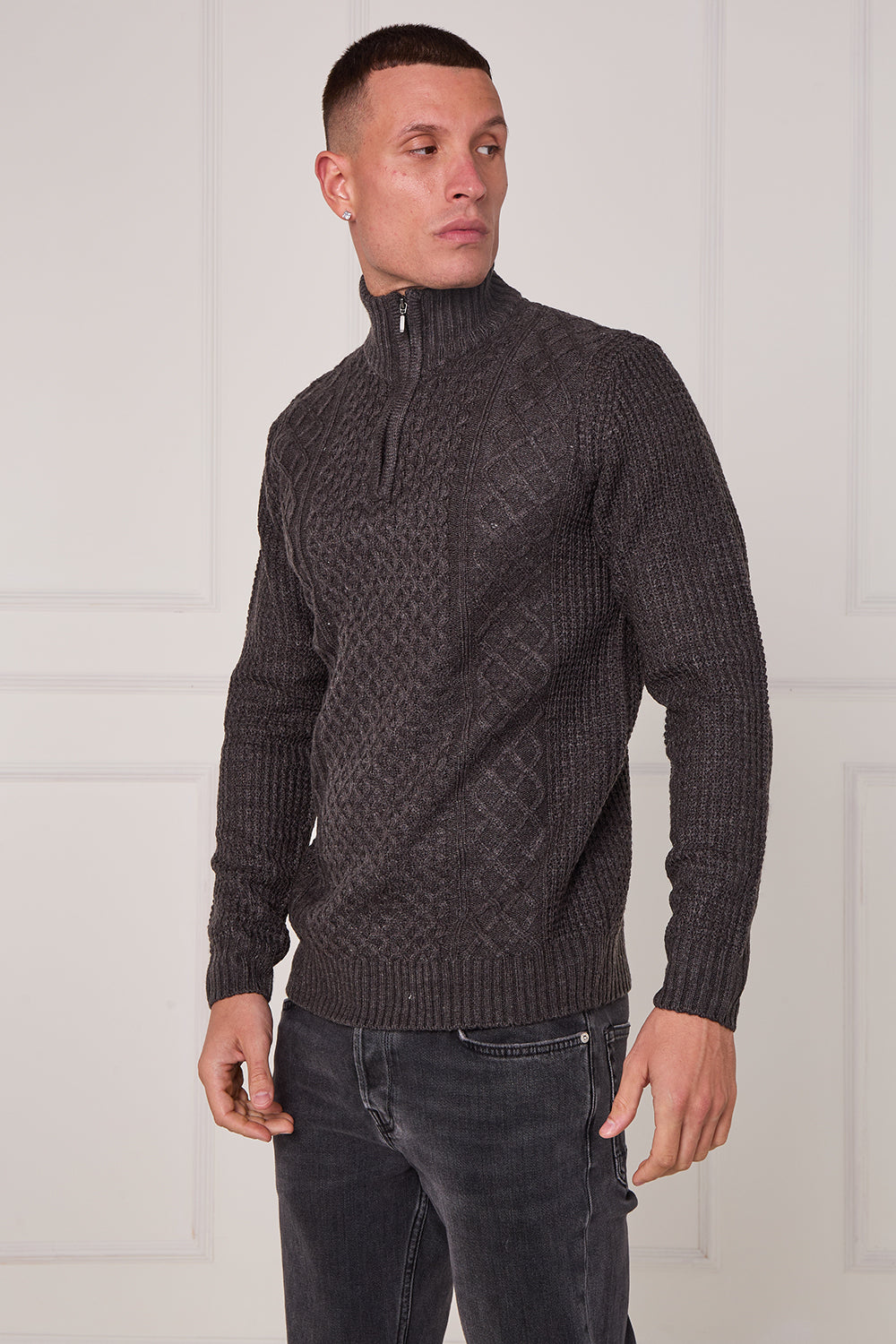 Man wearing a dark gray cable knit sweater with a zipper against a white background