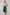 Woman wearing a beige top and green skirt against a white background