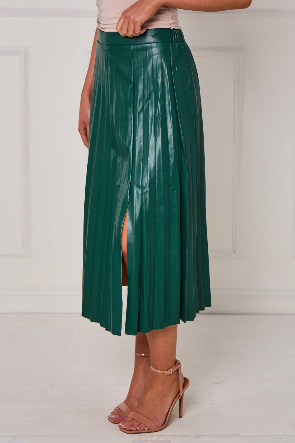 Green pleated skirt worn by a person on a white background