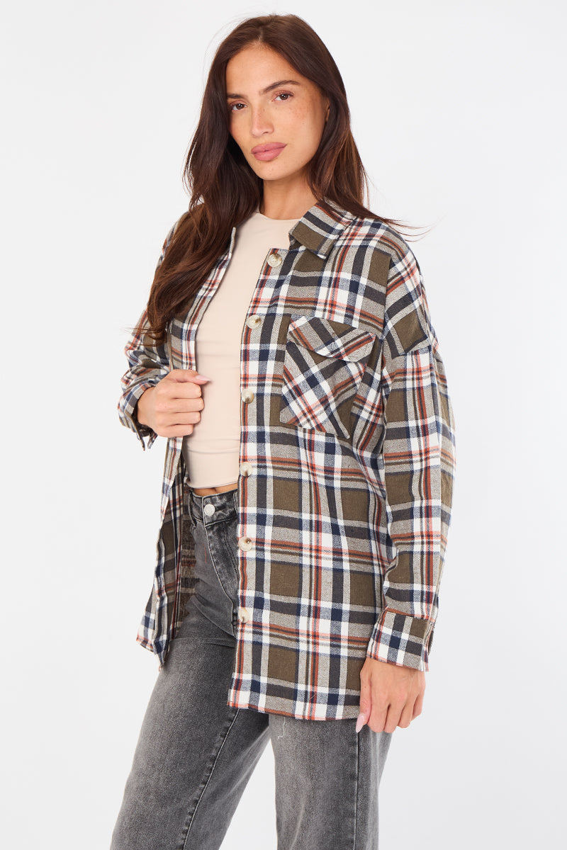 Woman wearing a plaid shirt over a beige top and jeans on a white background