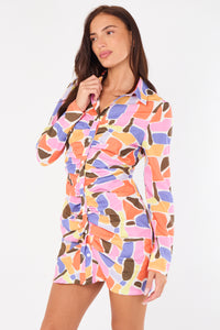 Woman wearing a colorful patterned shirt dress on a white background