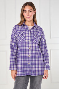 Woman wearing a purple plaid shirt against a white background