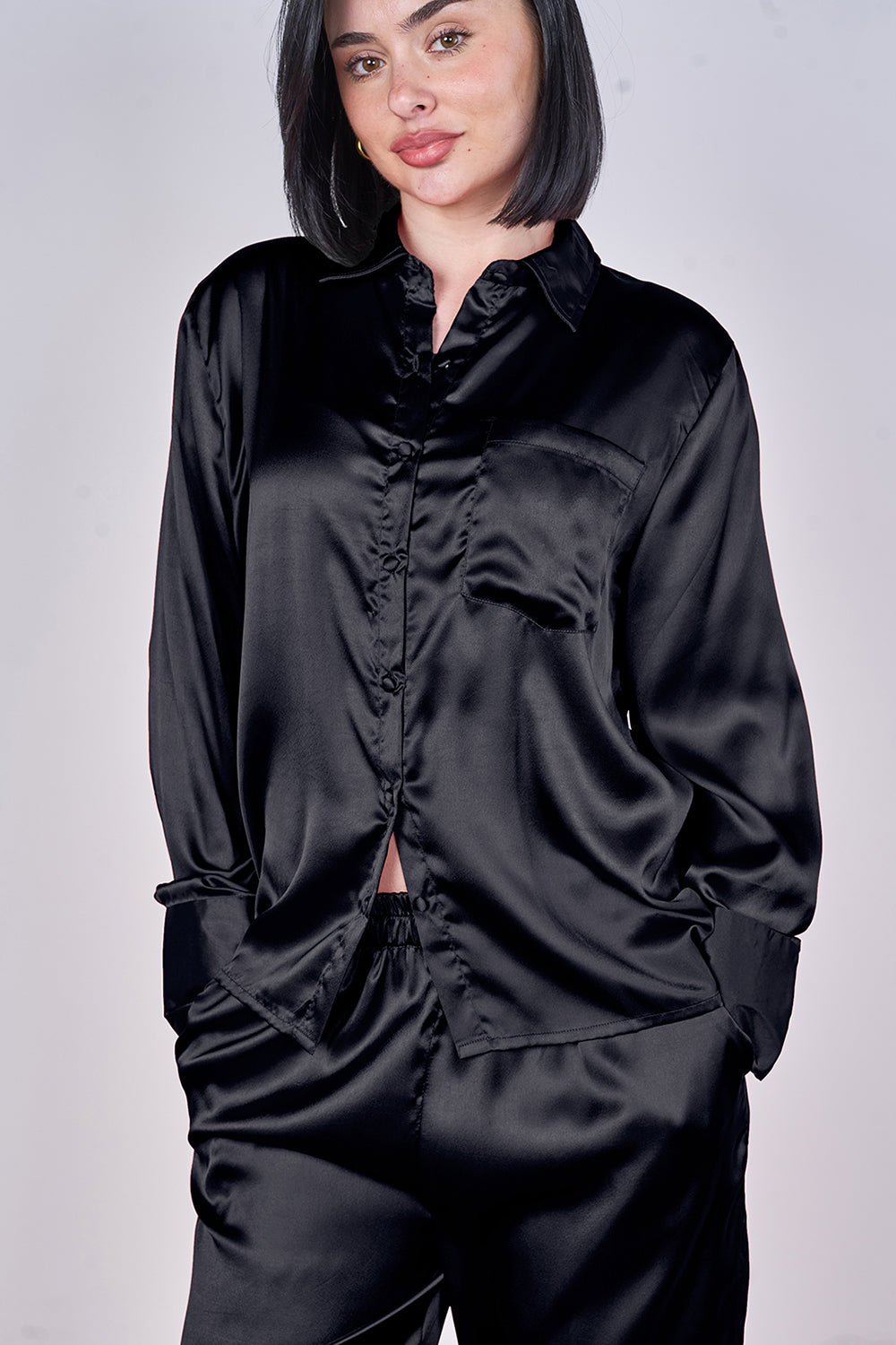 Person wearing a black satin outfit on a plain background