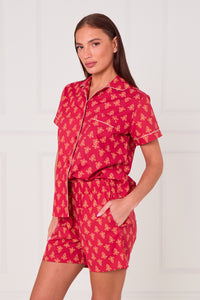 Woman wearing a red pajama set with yellow patterns on a white background