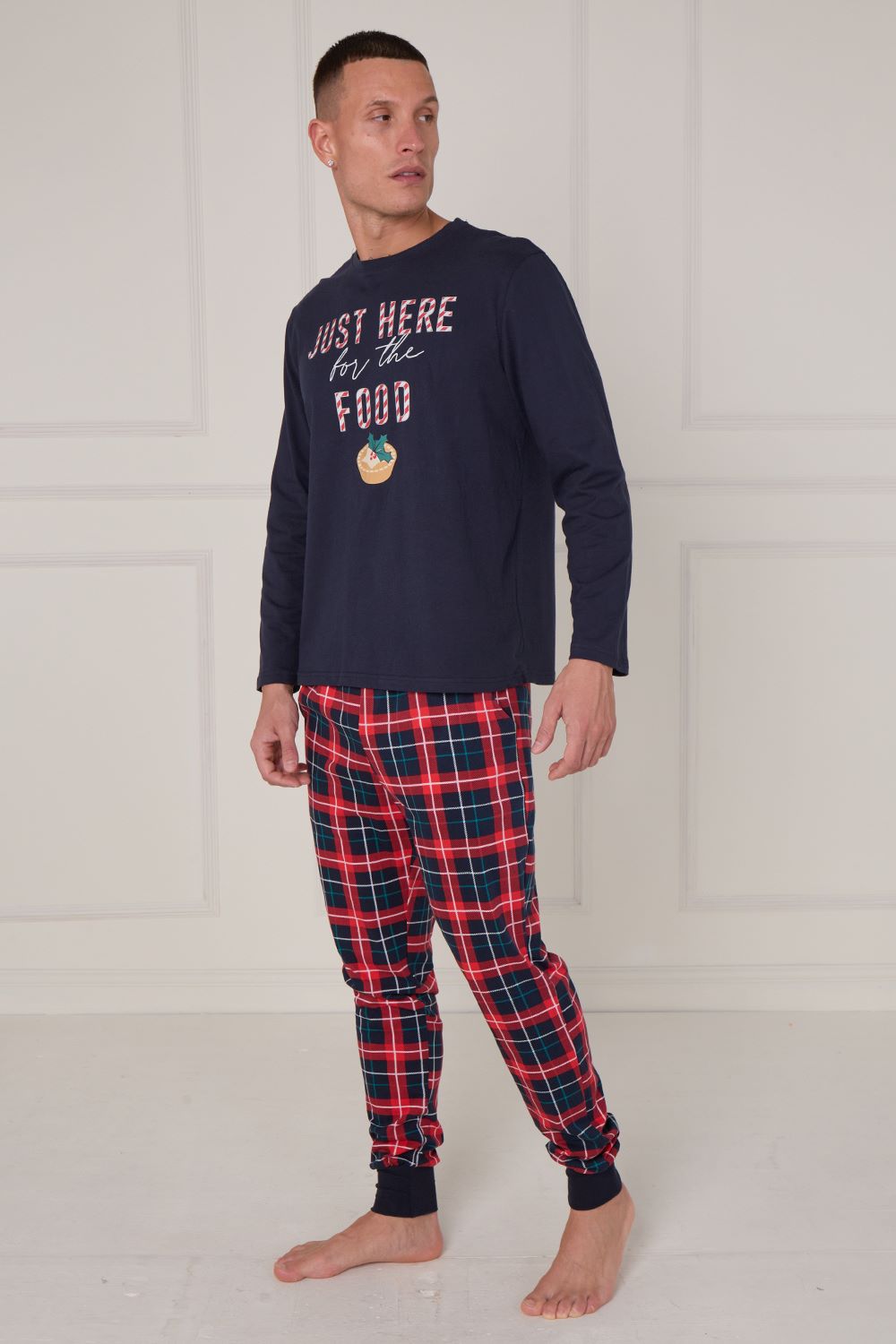Man wearing navy long-sleeve shirt with text and red plaid pants on a white background