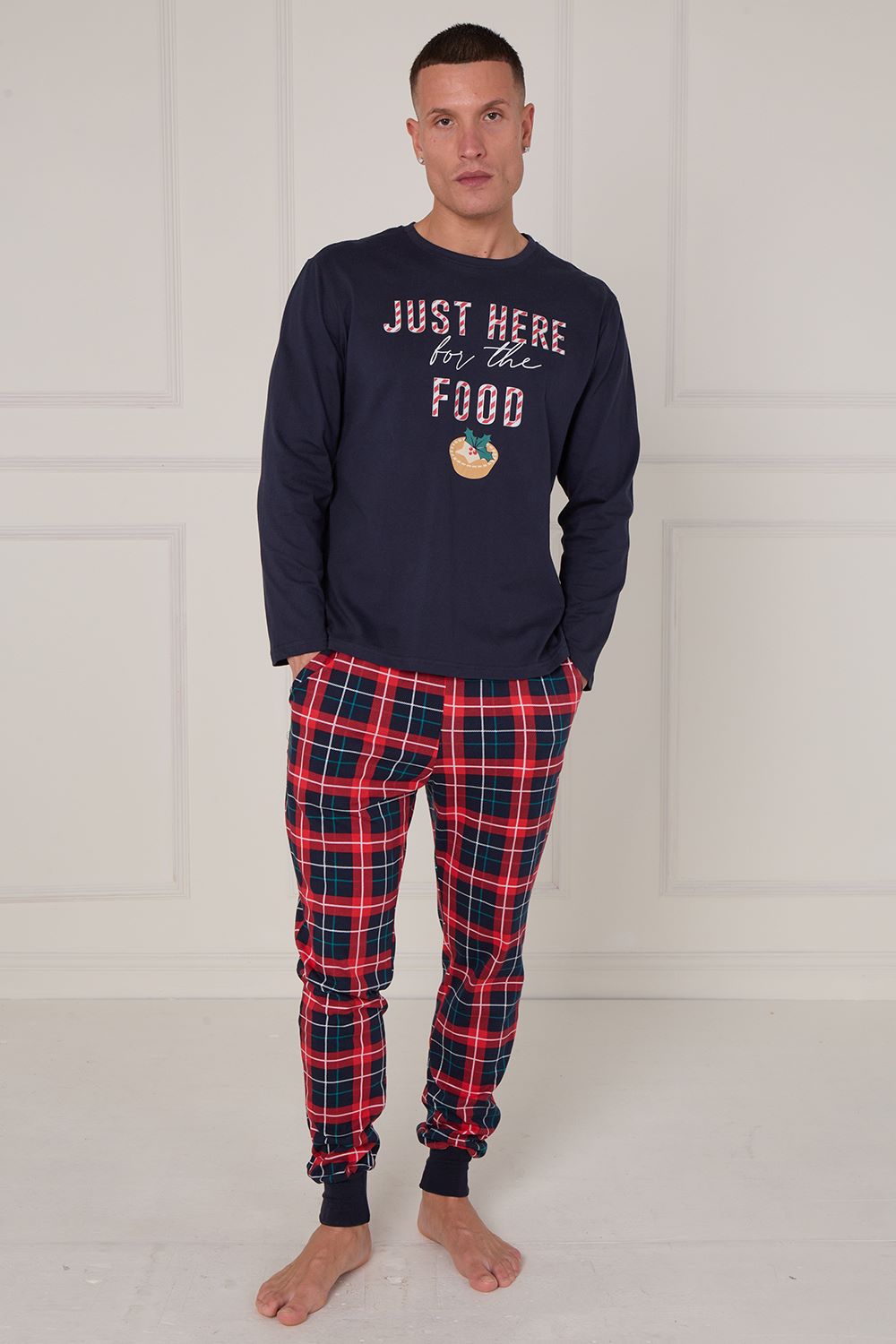 Man wearing navy sweatshirt with text and plaid pants on a white background
