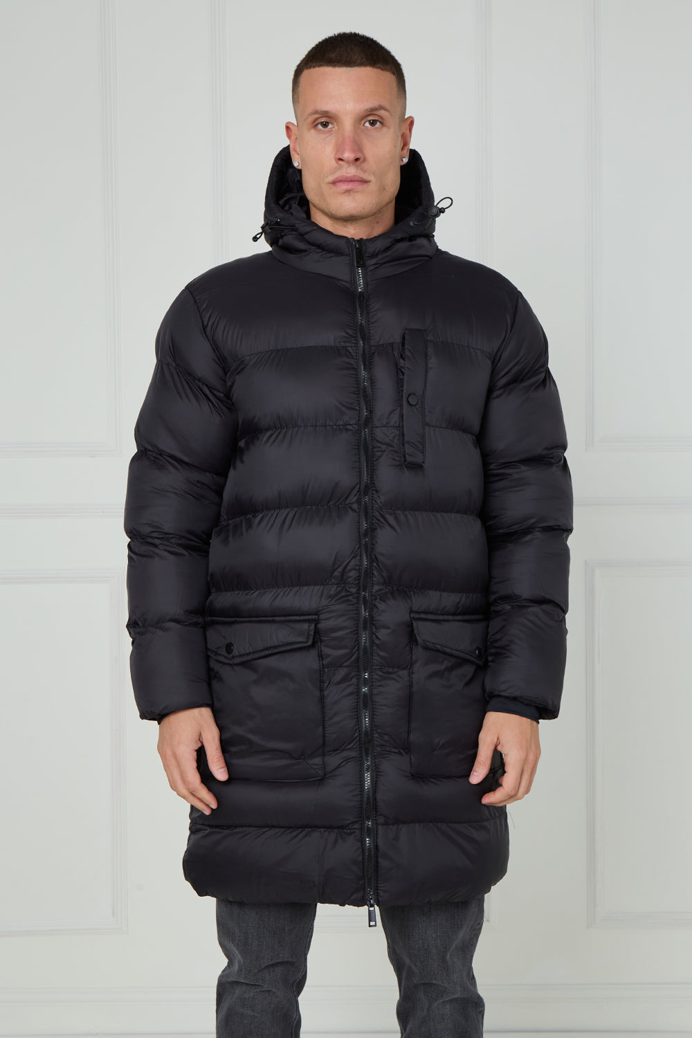 Man wearing a black puffer jacket against a white background