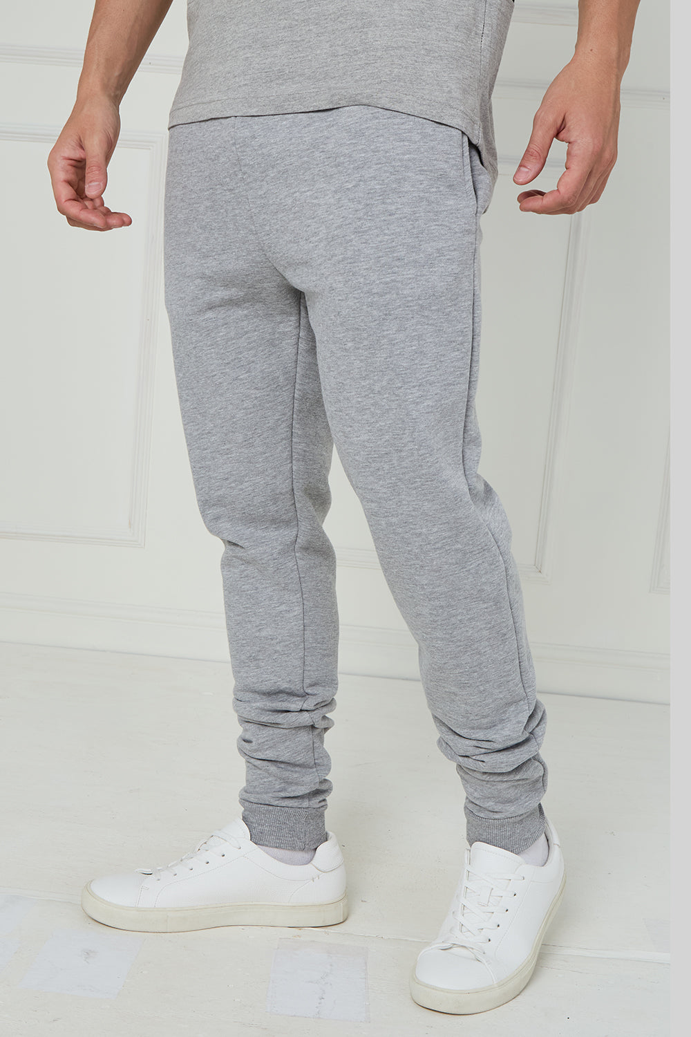Person wearing gray jogger pants and white sneakers on a white background