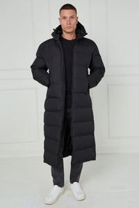 Man wearing a long black puffer coat against a white background